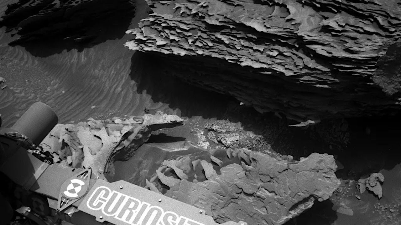 NASA's Mars rover Curiosity prepares for a thorough examination of the unusual, dark “Tungsten Hills” rocks in front of it, studying these rugged boulders covered in paper-thin sedimentary layers, some of which contain intriguing ripple structures that may have formed in running water or windblown sand. This image was taken by Left Navigation Camera aboard Curiosity on Sol 4298 — Martian day 4,298 of the Mars Science Laboratory mission — on Sept. 8, 2024, at 06:35:57 UTC. NASA/JPL-Caltech larger image -- NASA