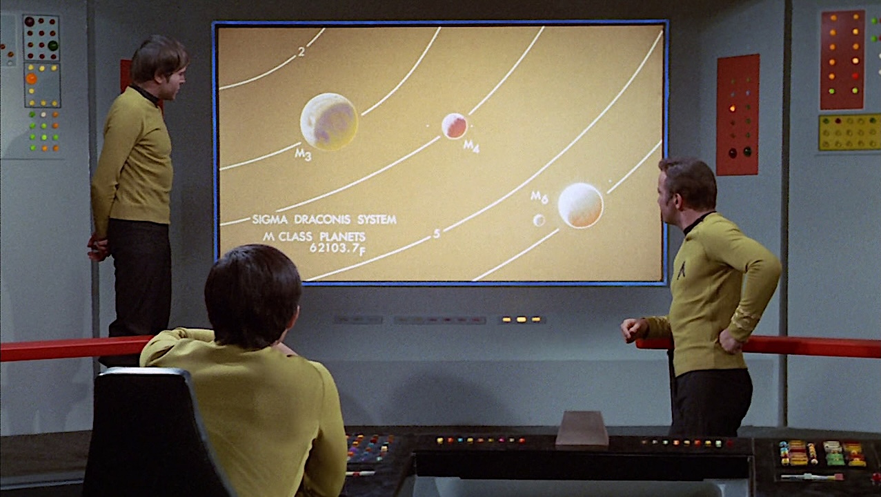 The crew of the Enterprise vies a map of the Sigma Draconis system and its three Class M planets - "Spock's Brain" - Paramount/CBS.