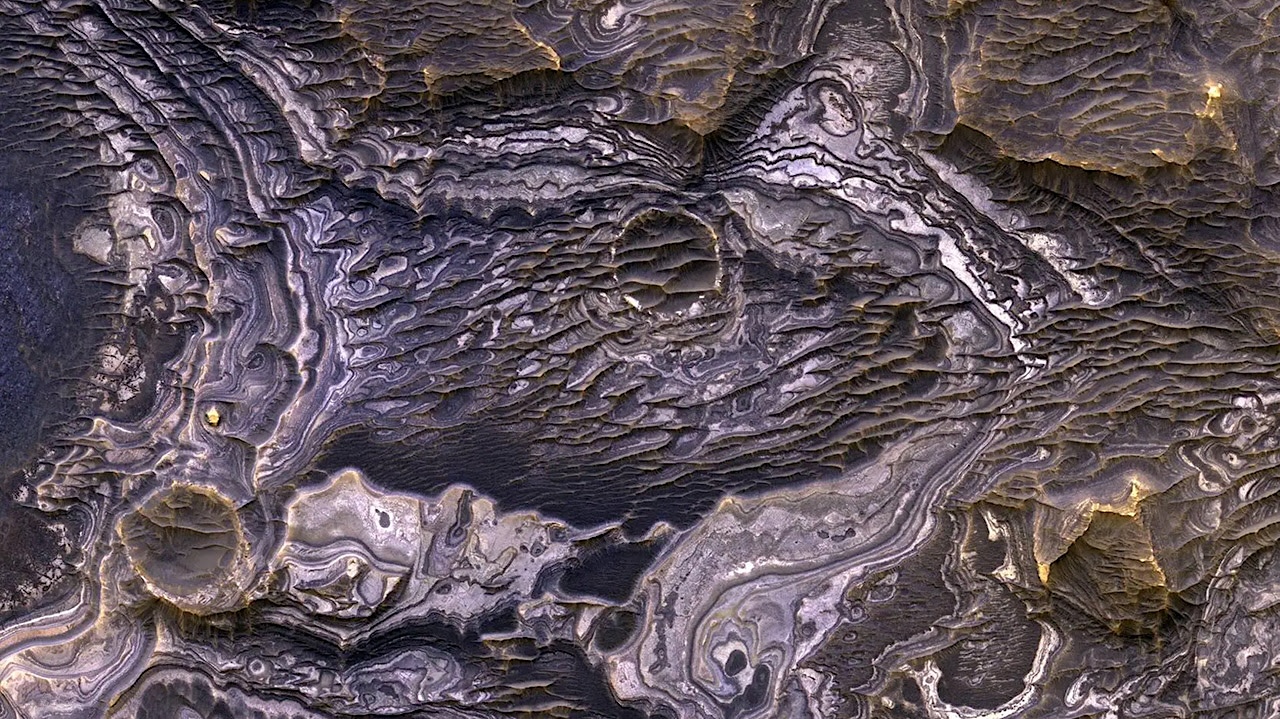 These Martian landforms were created when volcanic ash was modified by water to various degrees over millennia. These layered deposits are on a plateau near Juventae Chasma in the Valles Marineris region of Mars. Researchers have found that these bright layered deposits contain opaline silica and iron sulfates, which hint at their origins. Image credit: NASA/JPL-Caltech/University of Arizona
