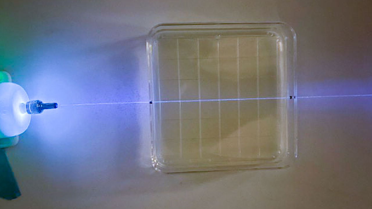 Germicidal UV light is emitted by an optical fiber running through the center of an agar plate. Researchers are testing whether microgravity changes the ability of the light to prevent growth of microbial communities known as biofilms. Credit: Arizona State University Larger image