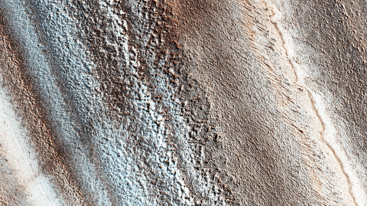 The North Polar layered deposits are a stack of ice-rich layers, with different layers likely having varying amounts of dust. uahirise Larger image